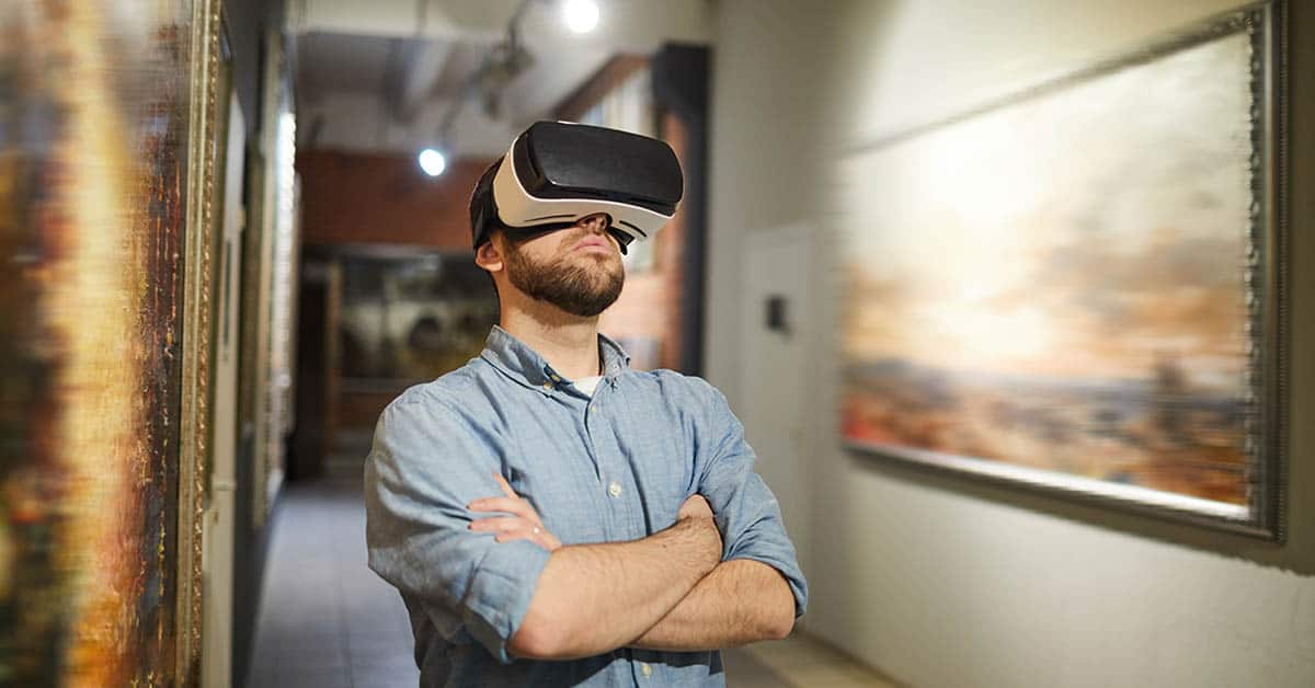 Porträt eines modernen Mannes in Taillenhöhe, der ein VR-Headset während eines virtuellen Rundgangs in einer Kunstgalerie oder einem Museum trägt